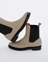 Bota Chelsea color hueso de cuero vacuno, con elástico lateral negro y suela de cuero.