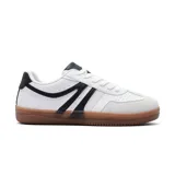 Championes deportivos de estilo urbano, con diseño inspirado en modelos clásicos de fútbol sala. Presentan una base de cuero sintético blanco con detalles en negro en los laterales y el talón, puntera reforzada en gamuza gris y suela de goma color caramelo.