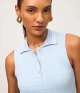 Blusa de punto color celeste sin mangas, con cuello polo y cierre frontal de tres botones. Presenta detalles de rayas blancas contrastantes en el cuello y tejido con textura de ochos.