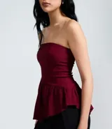 Blusa peplum sin tirantes de color negro, confeccionada en bengalina con diseño asimétrico en el dobladillo.