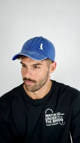 Gorra tipo baseball color azul con efecto desgastado y logo bordado en blanco en la parte frontal.