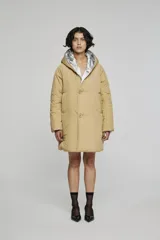 Campera reversible de corte regular, confeccionada en nylon con acabado repelente al agua. Presenta un diseño con capucha, mangas raglán y cierre frontal con botones. Un lado es de color beige y el otro lado es de color plateado metalizado.