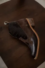 Botines de cuero color marrón oscuro con paneles laterales de gamuza negra, puntera con textura y tacón bajo.