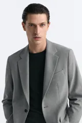 Blazer azul marino de corte recto, confeccionada en tejido con viscosa. Tiene cuello con solapas de muesca, manga larga con puño abotonado, bolsillo de vivo en el pecho y bolsillos de parche en la cadera. El bajo tiene aberturas en la espalda y el cierre es con botonadura frontal.