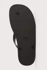 Sandalia de goma color negro, de diseño plano y tiras delgadas en el empeine estilo ojota.