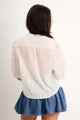 Camisa de algodón bordado color crudo, con cuello mao, manga 3/4 y cierre frontal con broches de estilo oriental.
