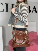 Bolso tipo marinero de cuero genuino negro, con cierre de cordón ajustable, correa corta de cuero y correa larga ajustable de tela.