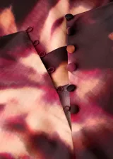 Blusa de cuello alto y manga larga con diseño recto y estampado tie-dye en tonos oscuros. Cuenta con cierre de botones en la parte posterior.