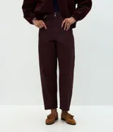 Pantalón modelo carrot de sarga, con cintura alta, pretina con presillas, cierre frontal con botón y cremallera, y bolsillos funcionales. Presenta un calce holgado en la cadera que se estrecha hacia el bajo.