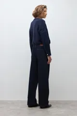 Pantalón de jean de corte wide leg en color azul oscuro, con tiro medio y cierre frontal con botón y cremallera.