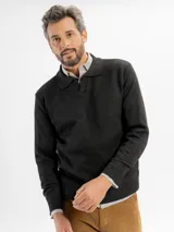 Buzo de tejido de punto en color negro, con cuello tipo polo y cierre frontal parcial. Presenta puños y ruedo acanalados.