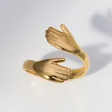 Set de dos anillos unisex, uno dorado y otro plateado, con diseño de manos abrazándose.