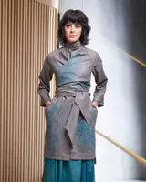 Túnica beige de gabardina de lana estampada con diseño abstracto en tonos ocre. Cuenta con cuello mao, bolsillos laterales y dos piezas a modo de bufandas que se pueden anudar de diferentes maneras.