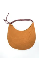 Bolso tipo morral color marrón de diseño curvo, con manija de cuerda trenzada en tonos burdeos y detalles de nudos en los extremos.