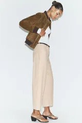 Pantalón tobillero de corte recto en color beige, con detalle de nervio delantero marcado. Incluye cinturón fino, bolsillos delanteros y cierre frontal con cremallera, botón interior y gancho.