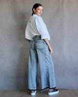 Pantalón de jean azul de tiro medio, con corte wide leg y ruedo deshilachado.