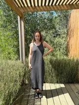 Vestido largo de punto, negro con rayas horizontales blancas, corte recto y sin mangas.