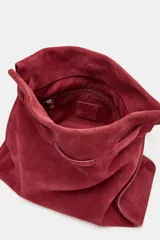 Bolso de hombro confeccionado en serraje color bordó, con diseño de tira entrelazada en la parte frontal, asa larga y cierre mediante botón imantado.
