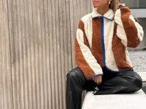 Campera de corderito con diseño de bloques de color, confeccionada en tejido sintético de textura suave. Presenta cierre frontal, cuello alto y ribetes en contraste en los bordes.