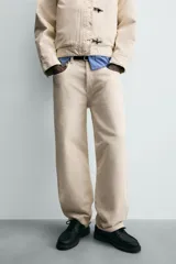 Jeans de hombre color beige claro, tiro medio, corte balloon fit con pierna relajada que se estrecha ligeramente hacia el bajo. Confeccionados en denim rígido de algodón, con cinco bolsillos y cierre frontal de cremallera y botón.