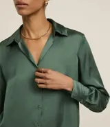 Camisa de satén color verde oliva, de manga larga con puños abotonados y cuello inglés.