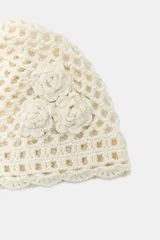 Gorro tipo casquete de crochet color crema, con tejido de red y tres flores aplicadas en relieve en un lateral.