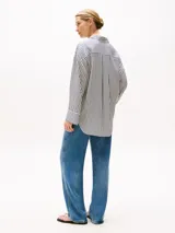 Camisa oversize de manga larga con cuello clásico y puños abotonados. Diseño a rayas verticales en blanco y azul marino.