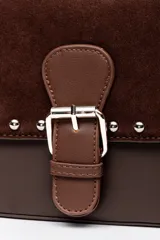 Bolso tipo cartera de mano color marrón, confeccionado en cuerina y gamuza, con solapa frontal decorada con tachas metálicas plateadas y una tira con hebilla central. Cuenta con un asa corta para llevar al hombro.