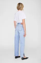 Jean de corte recto y relajado, confeccionado en denim rígido de algodón orgánico. Presenta un lavado azul medio con efecto desgastado y marmoleado, tiro alto, cierre con botones y aberturas laterales en los bajos.