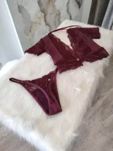 Conjunto de lencería compuesto por un top de encaje y satén con escote profundo y una tanga regulable a juego. El top presenta mangas cortas de encaje, detalles de puntilla en el escote y bajo, y cierre posterior. La tanga cuenta con detalles de encaje y forro de algodón.