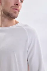 Remera manga larga de color blanco con cuello redondo a la base y mangas tipo raglán con textura acanalada.