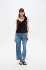 Musculosa de algodón color negro con escote en V profundo, tirantes finos y un volado diagonal fruncido que cruza desde el hombro izquierdo hasta el dobladillo.