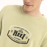 Buzo de cuello redondo marca Reef, color verde claro con efecto lavado. Presenta un estampado gráfico central con el logo de la marca y detalles en tonos oscuros.