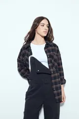 Camisa tipo leñadora de corte oversize, con estampado de cuadros en tonos negro y marrón. Presenta cuello clásico, cierre frontal con botones y mangas largas con puños abotonados.