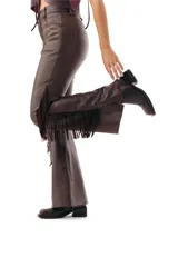 Pantalón semi oxford de cuero ovino color chocolate, con corte ajustado en la parte superior y botamanga acampanada, destacando flecos largos en los laterales.