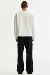 Pantalón cargo negro de sarga de algodón, con bolsillos laterales con solapa en las perneras y corte relajado.