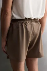 Pantalón corto deportivo color marrón oliva, confeccionado en tejido técnico ligero y elástico, con forro interior. Presenta cintura elástica ajustable con cordón, bolsillos frontales, bolsillo de seguridad trasero con cierre y aberturas laterales en el bajo.