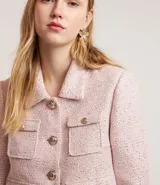 Campera corta de tweed color rosa, con cuello camisero, bolsillos delanteros con solapa y botones dorados estilo escudo.