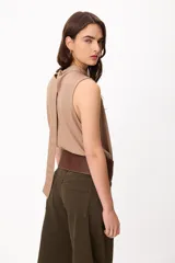 Blusa sin mangas color crema, con cuello alto fruncido y diseño holgado.