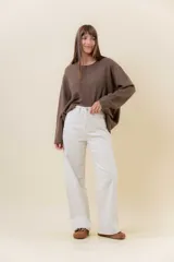 Jean wide leg de tiro alto en color crudo, con pierna amplia y costuras al tono. Cuenta con cierre frontal con botón, presillas en la cintura y bolsillos traseros clásicos.