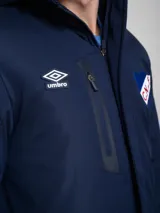 Parka larga de abrigo color azul marino, con capucha, cierre frontal, bolsillos con solapa y bolsillo superior con cierre. Presenta el logo de Umbro y el escudo del Club Nacional de Football.