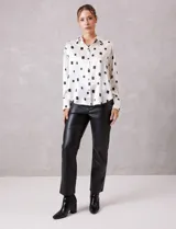 Camisa de satén con estampado de rectángulos negros sobre fondo blanco. Presenta cuello clásico con solapa, cierre frontal con botones metálicos y mangas largas con puños rectos.