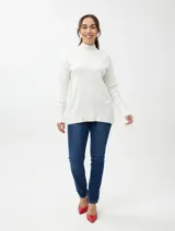 Buzo de punto en color beige, con cuello alto, mangas largas y terminaciones acanaladas en puños y ruedo.