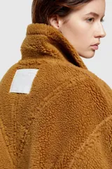 Chaqueta corta azul con efecto desgastado y cuello de piel sintética. Cuenta con cierre frontal con cremallera, dos bolsillos laterales con cremallera y puños y bajo con ribete de piel sintética.