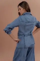 Chaqueta de jean azul, de corte entallado, con cuello camisero, cierre frontal con botones y bolsillos delanteros con solapa.