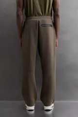 Pantalón jogger relaxed fit Zara Athleticz de tejido técnico compacto elástico con mezcla de algodón. Presenta cintura elástica ajustable con cordón, bolsillos laterales en la cadera, bolsillo trasero con cierre de cremallera, bajo ajustable con elástico y detalle de logo estampado en la pernera.