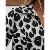 Conjunto de dos piezas compuesto por una camisa de manga corta con cuello italiano y cierre frontal de botones, y un short con cintura elástica y bolsillos laterales. Ambas prendas presentan un diseño estampado de animal print.
