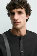 Camiseta de manga corta con cuello panadero y cierre frontal de tres botones. Presenta una textura acanalada y un corte regular fit.