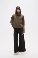 Buzo de cuello alto tipo polera, color verde oliva, con corte holgado, mangas largas y un bolsillo frontal aplicado en el pecho.