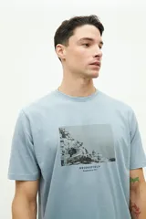 Remera de manga corta color beige con estampado fotográfico en el pecho. Presenta un corte regular y cuello redondo.